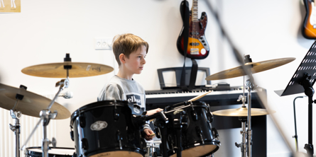 dreng ved trommesæt i musiklokale