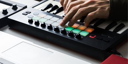 to hænder ved elektronisk musikudstyr